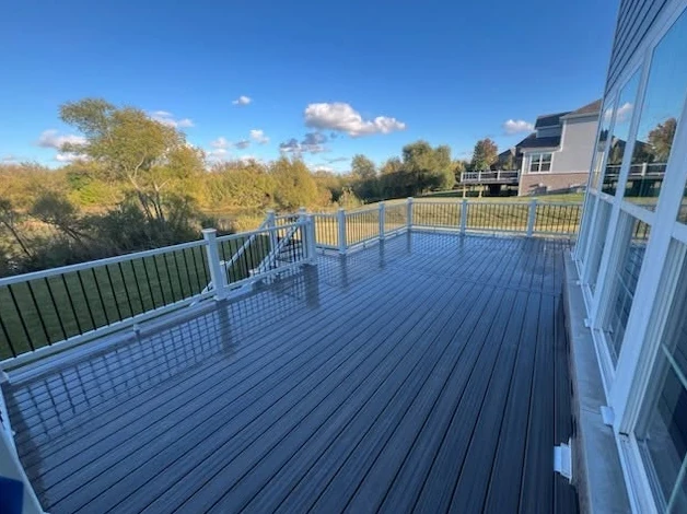 Gray deck overlooking trees and a pond