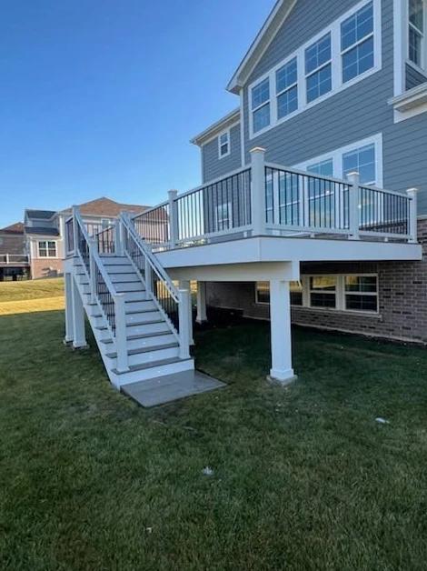 Raised gray deck with black railings and white stairs