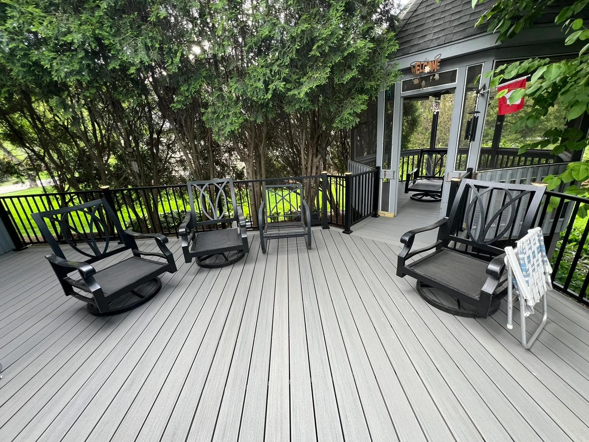 Gray deck furnished with chairs beside a screened porch