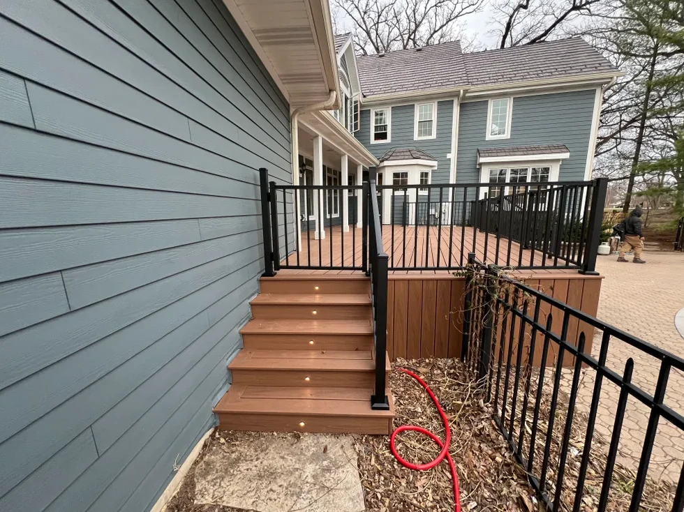 Finished deck stairs and railing beside a home