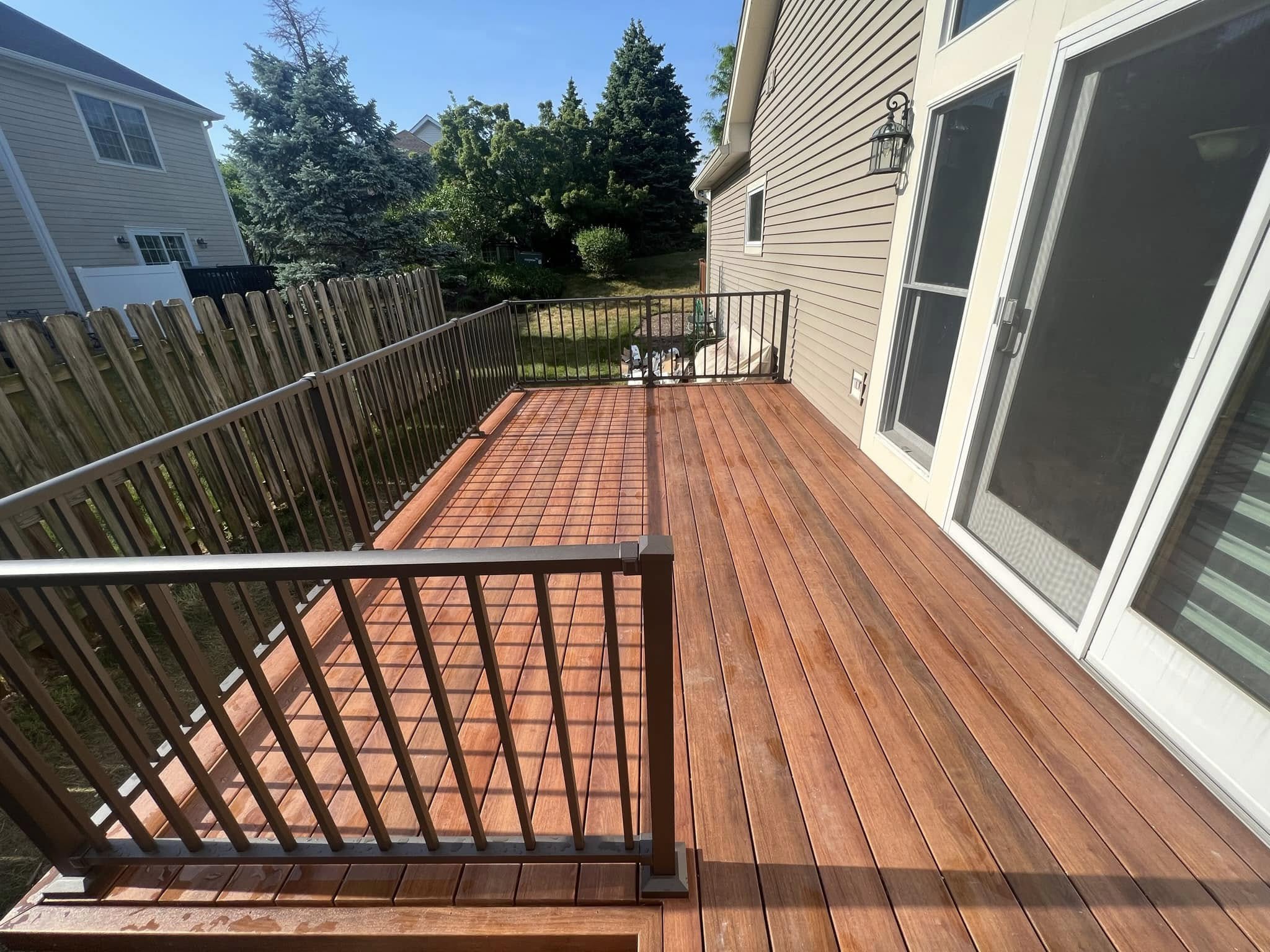 New stained wood deck in Buffalo Grove with dark railings beside a sliding glass door